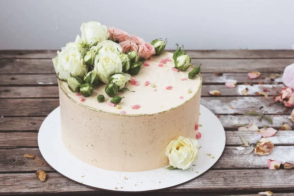 ケーキスタンドには新鮮な花で飾られたピンクのクリームケーキが木製のテーブルの上に立っています 選択的フォーカス 閉じろ — ストック写真