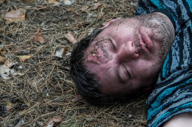 Ormanda cinayet. Ölü bir adamın kafası ormandaki ağaçların arasında yerde yatıyor. Bir saldırı kurbanı. Yatay fotoğraf. Kapat..