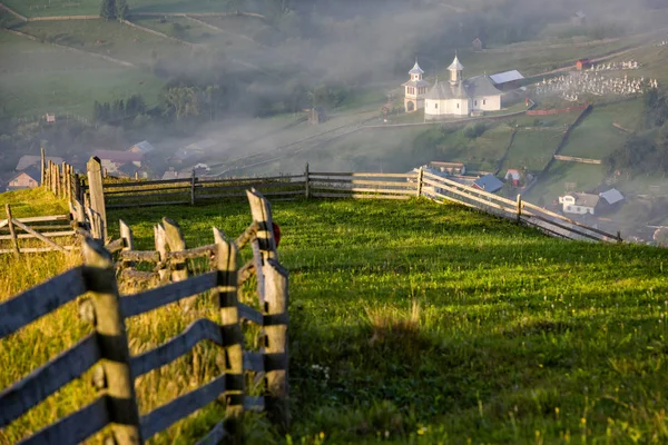 Romanya'da Bucovina yeşil tepelerin güzel gün doğumu sırasında üstünde uzak sisli Köyü