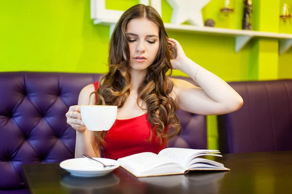 Woman reading book and drinking coffee at cafe — Stock Photo, Image