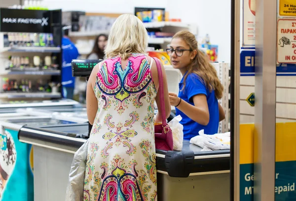 Woman is standing at the cash register and paying for the goods — Stock Photo, Image