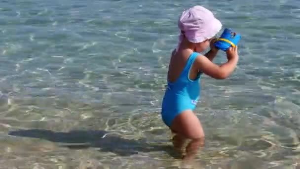 Kleines Mädchen im blauen Badeanzug spielt am Strand — Stockvideo