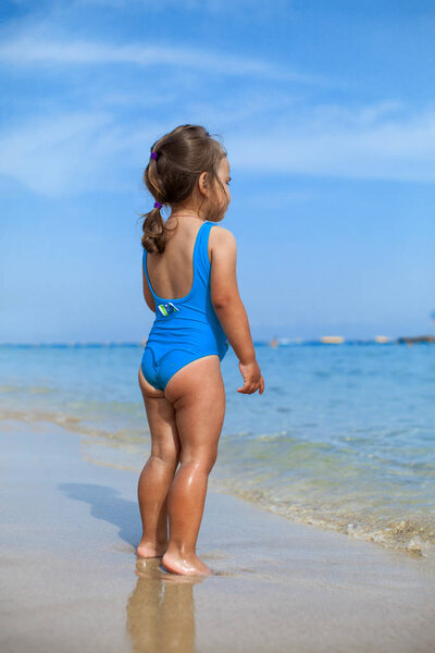 Adorable little girl standing on tropical beach