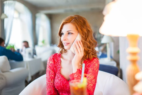 En ung kvinna som sitter på ett café med mobiltelefon — Stockfoto