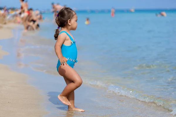 Adorable petite fille debout sur la plage tropicale — Photo