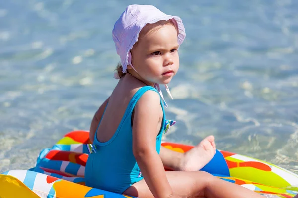 Criança menina está jogando na praia de areia perto do mar azul — Fotografia de Stock