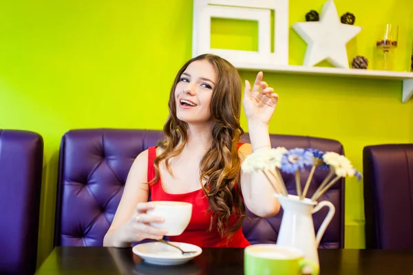 Uma jovem mulher bonita está bebendo café em um café — Fotografia de Stock