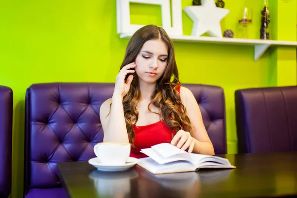 Uma jovem mulher bonita está bebendo café em um café — Fotografia de Stock