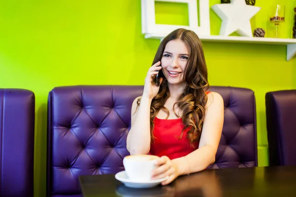 Una joven hermosa mujer está tomando café en un café — Foto de Stock