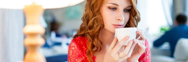 A young beautiful woman is drinking coffee in a cafe — Stock Photo, Image