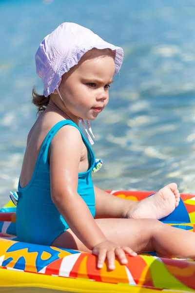 Child girl is playing on sandy beach near blue sea — Stock Photo, Image