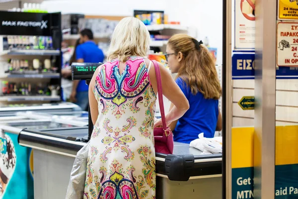 La mujer está parada en la caja registradora y pagando por los bienes — Foto de Stock