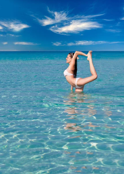 Una mujer está haciendo ejercicio de flexibilidad en el mar —  Fotos de Stock