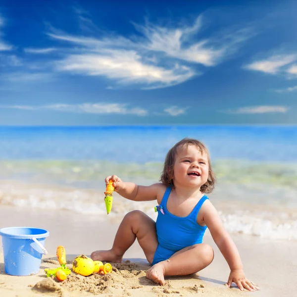 Little girl in blue swimsuit is playing in water — Stock Photo, Image