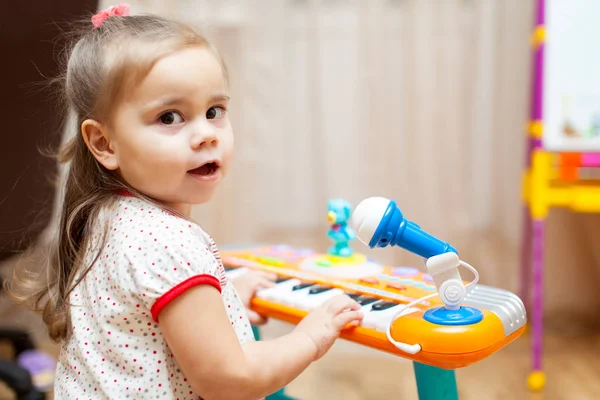 子小さな女の子がおもちゃのピアノで遊んで — ストック写真