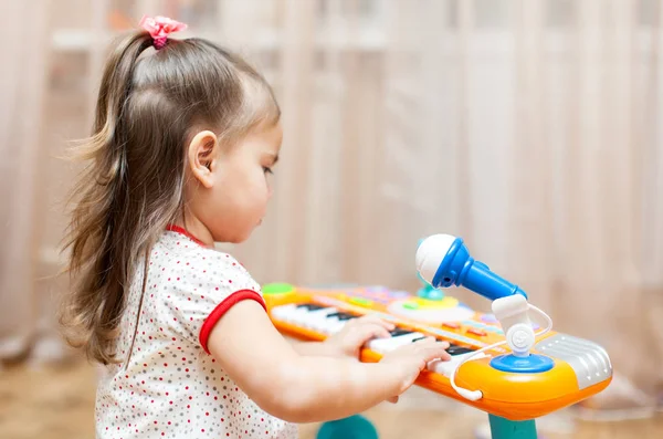 Девочка играет на игрушечном пианино — стоковое фото