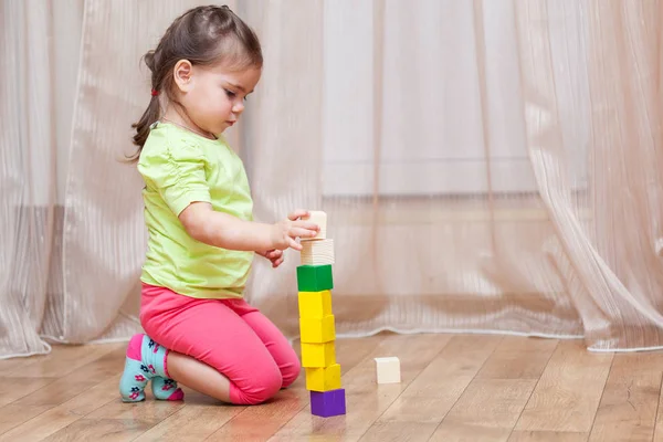 Cute little girl sitting on the floor and playing with building — Stock Photo, Image