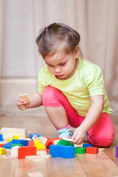 Cute little girl sitting on the floor and playing with building — Stock Photo, Image