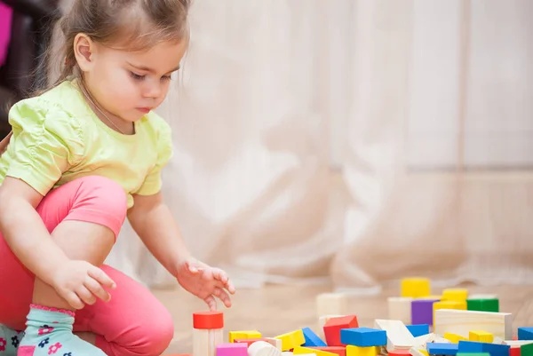 Cute little girl sitting on the floor and playing with building — Stock Photo, Image