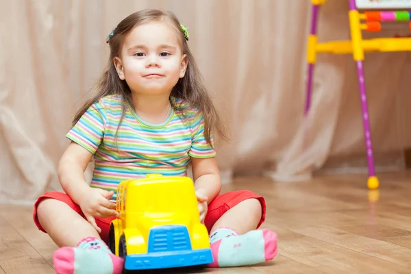 Child girl playing with a toy car on floor — Stock Photo, Image