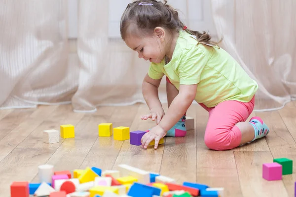 Cute little girl sitting on the floor and playing with building — Stock Photo, Image