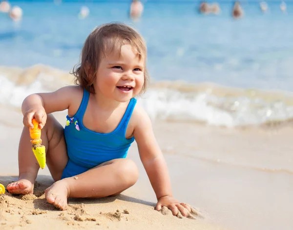 Little girl in blue swimsuit is playing in water — Stock Photo, Image