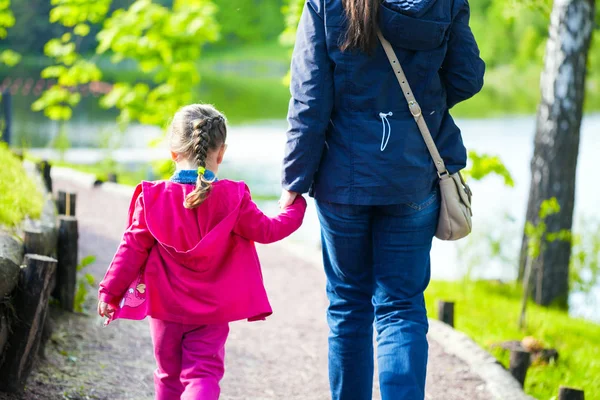 Joven madre y su pequeña hija caminando cerca del estanque en el parque —  Fotos de Stock