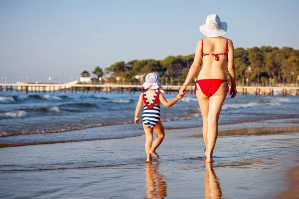 Vista trasera de la madre y la hija en la playa del mar —  Fotos de Stock