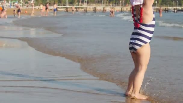 Мила дівчинка грає з іграшкою на літньому пляжі — стокове відео