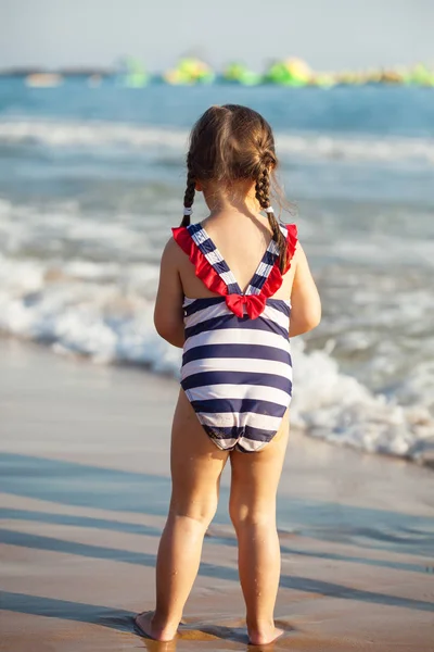 Zadní pohled na holčičku na pláži moře během letních prázdnin — Stock fotografie