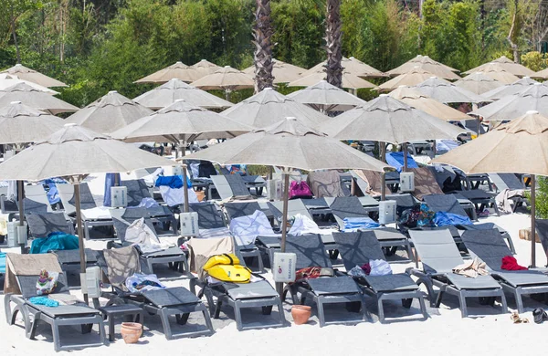 Chaises longues et parasols à la plage avec sable blanc — Photo