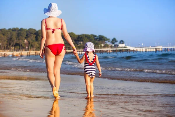 Mutter und Tochter spazieren am Strand bei Sonnenuntergang — Stockfoto