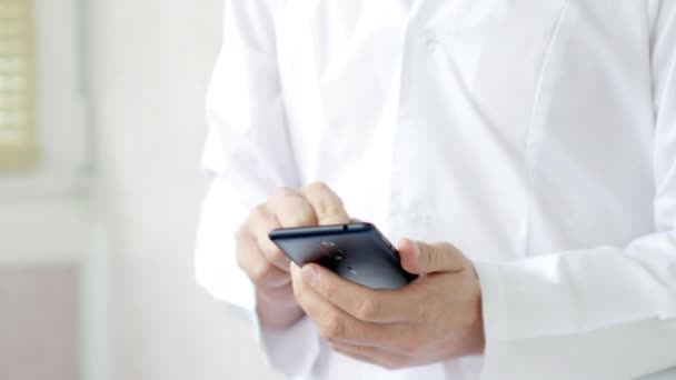 Maschio medico in cappotto bianco sta utilizzando un moderno dispositivo smartphone con touch screen — Video Stock