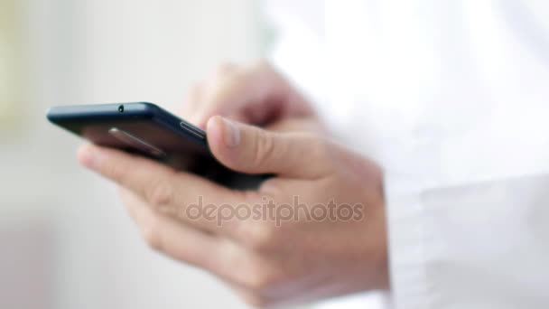 Médico masculino em casaco branco está usando um dispositivo de smartphone moderno com tela sensível ao toque — Vídeo de Stock