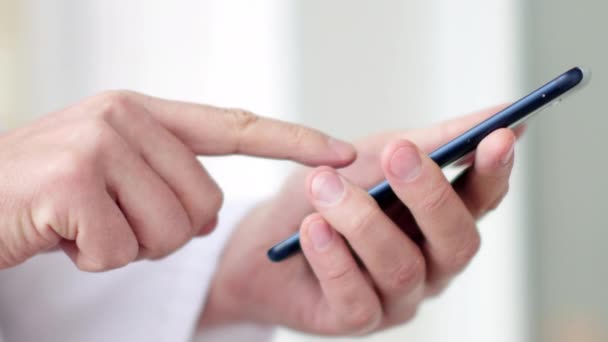 Мужчина врач в белом халате использует современное устройство смартфона с сенсорным экраном — стоковое видео