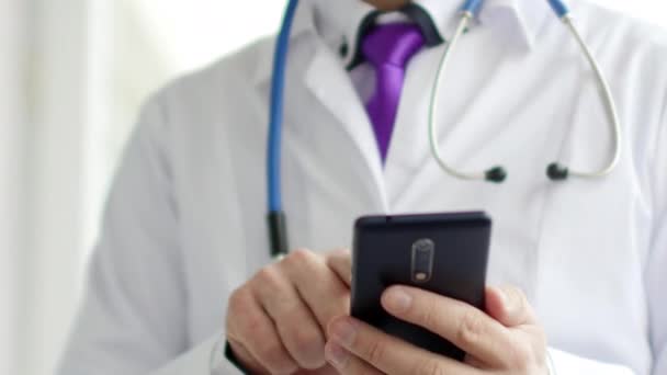 白いコートの男性医師がタッチ スクリーンの近代的なスマート フォンのデバイスを使っています。 — ストック動画
