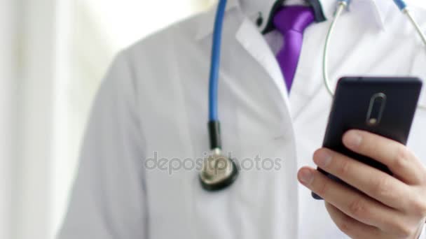 Male doctor in white coat is using a modern smartphone device with touch screen — Stock Video