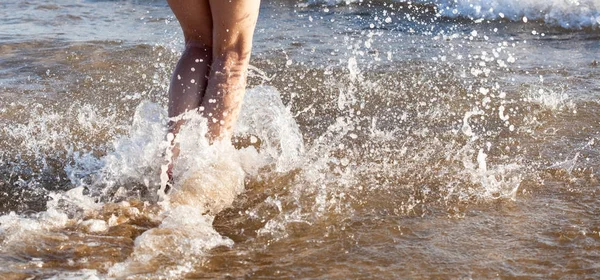 Mooie vrouwelijke benen op het strand met waterspatten — Stockfoto