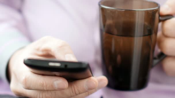 Бизнесмен со смартфоном пьет чай. 4K UltraHD видео — стоковое видео