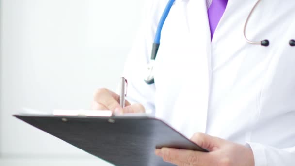 Medical doctor writing a prescription on a clipboard in the hospital. — Stock Video