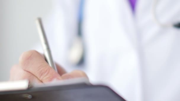 Medical doctor writing a prescription on a clipboard in the hospital. — Stock Video