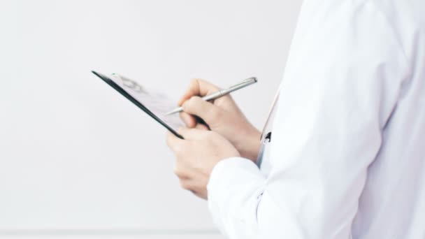 Médico médico que escribe una receta en un portapapeles en el hospital . — Vídeos de Stock