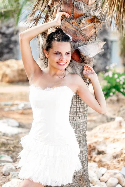 Frau im weißen Kleid am tropischen Strand in der Nähe von Palmen. — Stockfoto