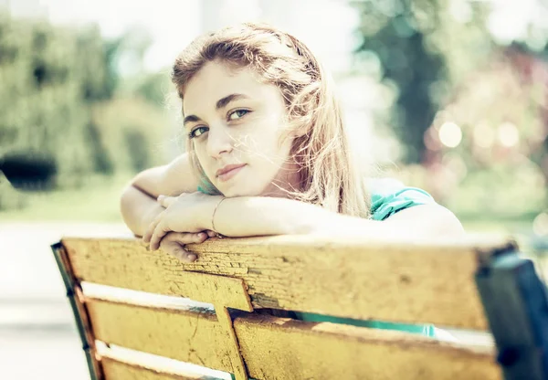 Jovem adolescente sentada no banco no parque — Fotografia de Stock