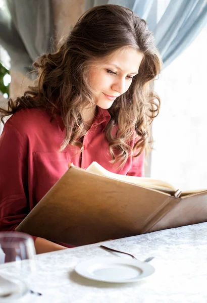 Schöne Frau schaut sich Speisekarte an und bestellt Lebensmittel im Café — Stockfoto