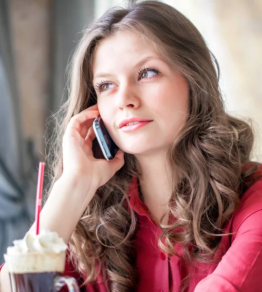 Porträtt av glad kvinna som håller mobiltelefon och kopp kaffe i moderna café — Stockfoto