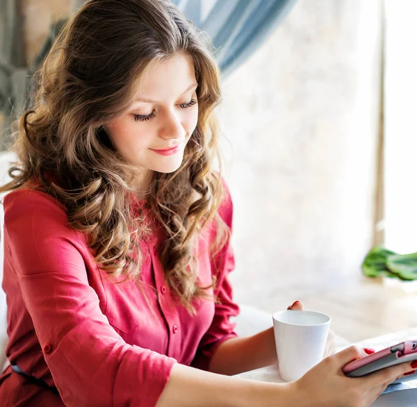 Ung vacker kvinna sitter vid bordet i ett kafé och med hjälp av tablet PC — Stockfoto