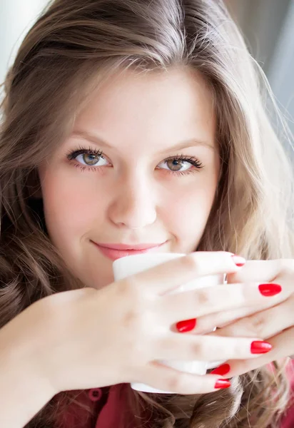 Mujer joven bebiendo café caliente en un café — Foto de Stock