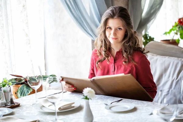 Mulher bonita olhando para o menu e encomendar alimentos no café — Fotografia de Stock