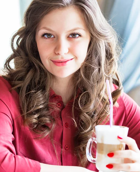 Mooie jonge vrouw drinken koffie latte in een café — Stockfoto